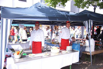 Foto: Zwei Helfer der Kochgruppe des DRK Siegburg an einem Straßenstand.